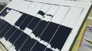 Aerial view of house roof with solar panels covered with snow melting down in winter end for producing clean energy. Concept of low effectivity of renewable electricity in northern region.