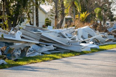 Kasırganın yol kenarındaki metal çöpler Florida yerleşim bölgesindeki evlere ağır hasar vermiş. Doğal afetten sonra.