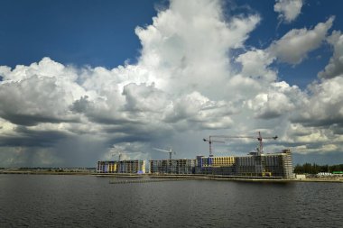 Deniz kıyısındaki yüksek konutlu apartman şantiyesinde vinç kaldırma. Gayrimenkul geliştirme.