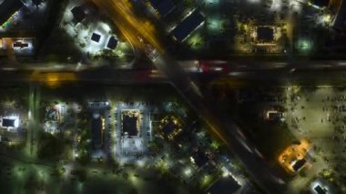 Gece vakti Amerikan şehrinde trafik ışıkları ve hareket halindeki arabaların kesiştiği büyük çok şeritli kavşağın üst görüntüsü. ABD 'de ulaşım sisteminin zamanlaması.