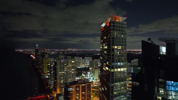 米国フロリダ州のサニーアイルズビーチシティのダウンタウン地区にある明るく照らされた高層ビルの上からの眺め 夜のアメリカの観光都市地区 — ストック動画