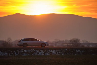 Gün batımında şehir içi yolda hızlı giden bir araba. Akşamları otoyol trafiği.