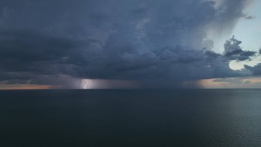 Şiddetli yağış mevsiminde gün batımında okyanus yüzeyinde kara uğursuz fırtına bulutları bulutları oluşuyor..