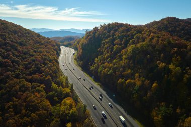 I-40 freeway road leading to Asheville in North Carolina thru Appalachian mountains with yellow fall forest and fast moving trucks and cars. Concept of high speed interstate transportation.