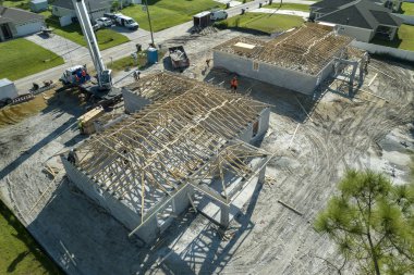 Vinç kamyonu ve inşaat işçileri Florida banliyö bölgesinde ahşap çerçeveli bitmemiş bir konut inşaatında çalışıyorlar. Konut geliştirme kavramı.