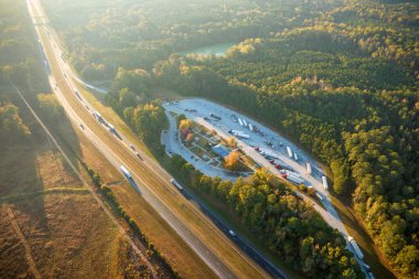 Top view of large rest area near busy multilane american freeway with fast moving cars and trucks. Recreational resting place during interstate traveling.