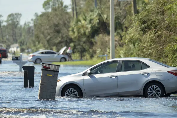 Flooded American street with stuck vehicle surrounded with water in Florida residential area. Consequences of hurricane natural disaster.