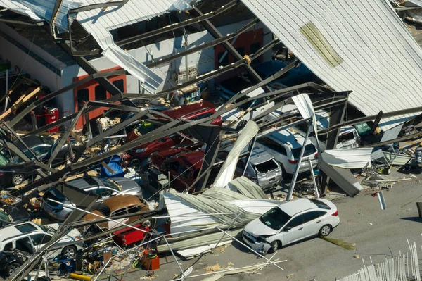 Automotive workshop destroyed by hurricane wind with damaged cars under ruins in Florida. Consequence of natural disaster.