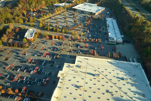 View from above of american grocery store with many parked cars on parking lot with lines and markings for parking places and directions. Place for vehicles in front of a strip mall center.
