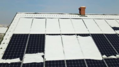 Aerial view of snow melting from covered solar photovoltaic panels installed on house rooftop for producing clean electrical energy. Low effectivity of renewable electricity in nothern region winter.