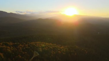 Güzel bir akşam panoramik manzarası. Gün batımında uzak dağ tepeleri üzerinde parlak batan güneş..