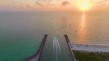 Venedik Güney Jetty ve Nokomis Kuzey Jetty eğlence amaçlı motorlu tekneleri ve yatları ile ABD 'nin Sarasota İlçesi körfezinde gün batımında yelken açıyorlar..