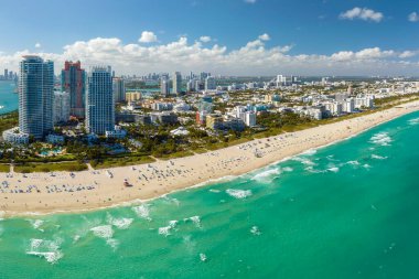 Sıcak Florida güneşinde dinlenen turistlerle birlikte güney sahilinin kumlu yüzeyi. Yüksek lüks otelleri ve apartmanları olan Miami Beach City. Güney Amerika 'da turizm altyapısı.