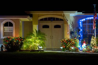 Florida aile evinin ön bahçesinde parlak ışıklandırılmış noel süslemeleri. Kış tatili için dışarıda dekor.