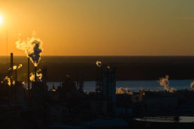 Yüksek bacaları olan büyük bir fabrika. Fabrika fabrikasındaki karbondioksit dumanıyla atmosferi kirletiyor. Gün batımında sanayi bölgesi.