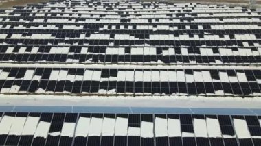 Aerial view of electrical power plant with solar panels covered with snow melting down in winter end for producing clean energy. Concept of low effectivity of renewable electricity in northern region.