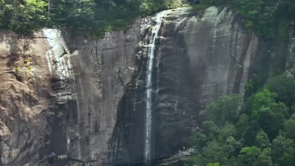 美国北卡罗莱纳州Chimney Rock州立公园山核桃树瀑布的空中景观 清澈的水从青翠茂密的树林之间的岩石巨石上落下来 — 图库视频影像