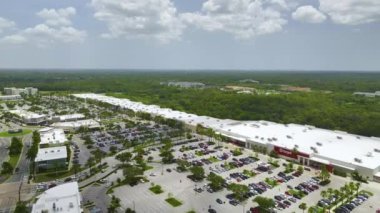 Aerial view of large parking lot with many parked colorful cars. Carpark at supercenter shopping mall with lines and markings for vehicle places and directions.