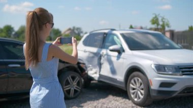 Stresli kadın sürücü, trafik kazası üstüne trafik kazası sonrası cep telefonu kamerasıyla fotoğraf çekiyor. Yol güvenliği ve sigorta kavramı.