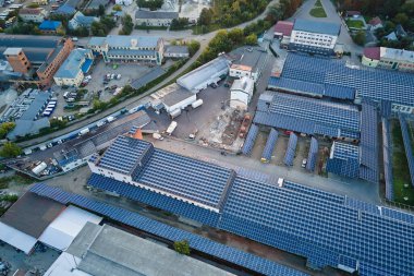 Sanayi binasının çatısına yeşil ekolojik elektrik üretmek için monte edilen mavi fotovoltaik güneş panellerinin hava görüntüsü. Sürdürülebilir enerji konsepti üretimi.