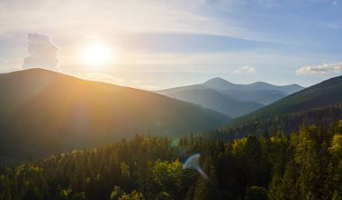 Parlak günbatımında karanlık çam ağaçları olan yüksek tepelerin üzerindeki sisli akşamın havadan görüntüsü. Karanlık çöktüğünde vahşi dağ ormanlarının muhteşem manzarası..