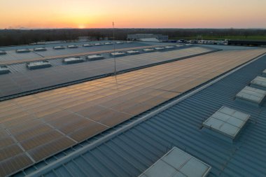 Mavi fotovoltaik güneş panelleri gün batımında temiz ekolojik elektrik üretmek için çatıya monte edildi. Yenilenebilir enerji konsepti üretimi.