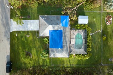 Ian Kasırgası, asfalt kiremitleri değişene kadar yağmur suyuna karşı koruyucu plastik muşambayla kaplı evin çatısına zarar verdi. Doğal afetten sonra.