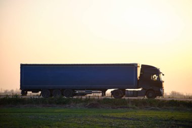 Kargo karavanı olan yarı kamyon akşam vakti otobanda mal taşır. Teslimat ulaşım ve lojistik kavramı.