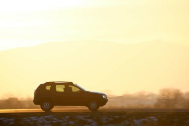 Gün batımında şehirlerarası yolda hızla giden bir SUV arabası. Akşamları otoyol trafiği.