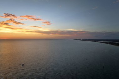 Gün batımında deniz dalgaları üzerinde yüzen yalnız beyaz yatın havadan görünüşü. Okyanus yüzeyinde motorlu tekne tatili.