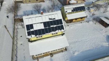 Aerial view of house roof with solar panels covered with snow melting down in winter end for producing clean energy. Concept of low effectivity of renewable electricity in northern region.