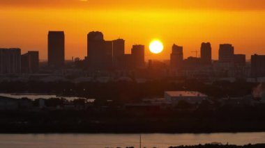 Ticari jet uçağı Florida, ABD şehir merkezindeki Tampa şehrinin şehir batımında havalanır. Modern Amerikan megapolis 'inde yüksek gökdelen binaları olan dramatik bir siluet..