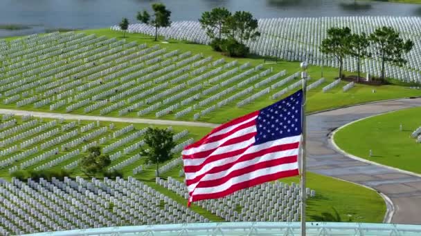 記念の日のコンセプト サラソータ国立墓地にはアメリカ国旗が掲げられ 緑の草の上に白い墓石が並んでいる — ストック動画