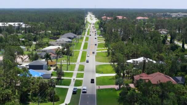 フロリダ州のアメリカの小さな町の農村道路交通 静かな住宅街の緑の木と郊外の通りの間の私的な家 — ストック動画