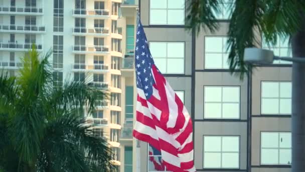マイアミの都市スカイラインの前に風を振るアメリカの国旗 アメリカの星とストライプは 民主主義の象徴としての旗を振った — ストック動画