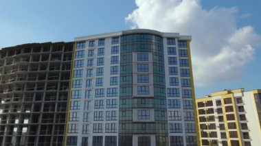 High residential apartment building with monolithic frame and glass windows under construction. Real estate development.