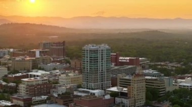 ABD 'nin seyahat rotasının havadan görüntüsü. Kuzey Carolina 'daki Asheville şehrinde günbatımında yüksek şehir binaları ve Appalachian dağ tepeleri var..