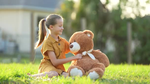 快乐的少女在绿草草坪上拥抱她的玩具熊朋友 友谊概念 — 图库视频影像