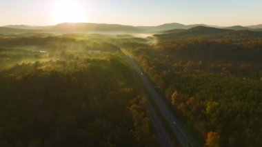 Sonbahar ormanları arasında hızla ilerleyen yoğun Amerikan otobanının manzarası. Eyaletler arası ulaşım kavramı.