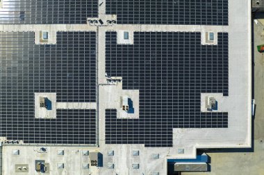 Mavi fotovoltaik güneş panelleri temiz ekolojik elektrik üretmek için endüstriyel binaların çatısına monte edildi. Yenilenebilir enerji konsepti üretimi.