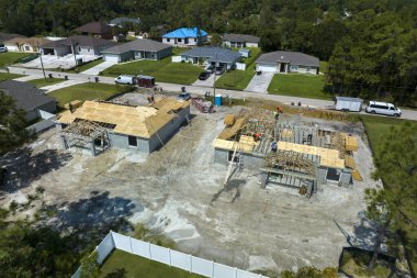 Florida 'nın banliyö bölgesinde inşaat halindeki ahşap çatı iskeleti yapısı olan bitmemiş bir ev üzerinde çalışan inşaatçıların hava görüntüsü..