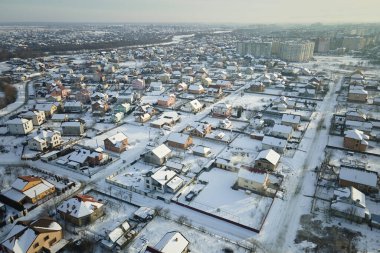 Soğuk kış mevsiminde kırsal kesimlerdeki çatıları karla kaplı özel evlerin hava manzarası..