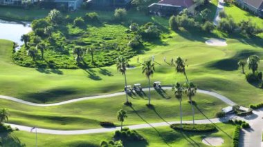Güneşli Florida 'daki geniş yeşil golf sahasında antrenman yapan oyuncuların hava görüntüsü. Zengin insanların aktif yaşam tarzı.