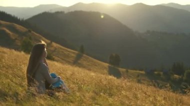 Yürüyüş yapan kadın dağ yolunda duruyor ve vahşi doğa yolculuğunda akşam doğasının tadını çıkarıyor. Yüksek tepe yolundan geçen yalnız bir kadın gezgin. Sağlıklı yaşam tarzı kavramı.