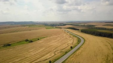 Sarı tarım buğday tarlaları arasında giden arabalarla dolu bir yolun havadan görünüşü yaz sonlarında hasat edilmeye hazır..