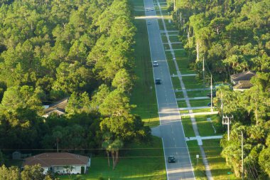 Aerial view of american small town in Florida with private homes between green palm trees and suburban streets in quiet residential area.