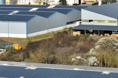 Sanayi binasının çatısına yeşil ekolojik elektrik üretmek için monte edilen mavi fotovoltaik güneş panellerinin hava görüntüsü. Sürdürülebilir enerji konsepti üretimi.