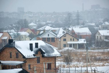 Soğuk kış mevsiminde kırsal kesimlerdeki çatıları karla kaplı özel evlerin hava manzarası..