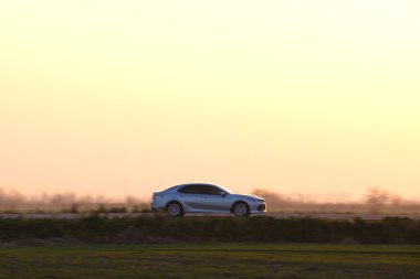Gün batımında şehir içi yolda hızlı giden bir araba. Akşamları otoyol trafiği.