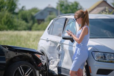 Üzgün kadın sürücü cadde tarafında cep telefonuyla konuşuyor. Araba kazasından sonra acil servisi arıyor. Yol güvenliği ve sigorta kavramı.